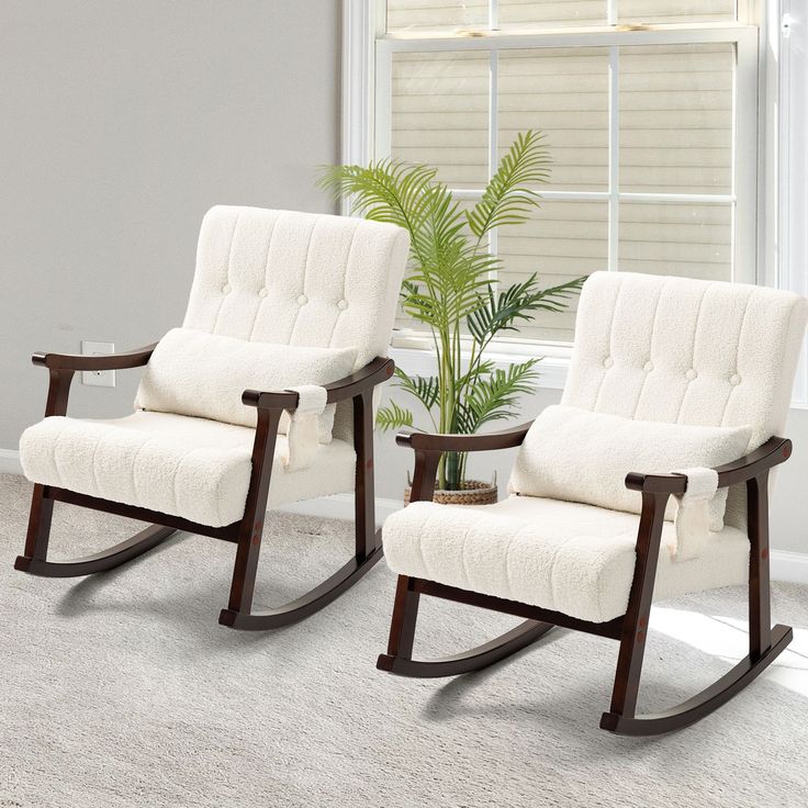 two white rocking chairs sitting next to each other in front of a potted plant