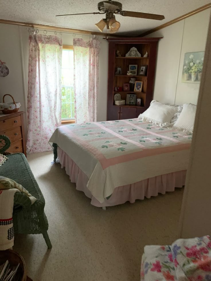 a bed sitting in a bedroom next to a window with pink and white bedspread