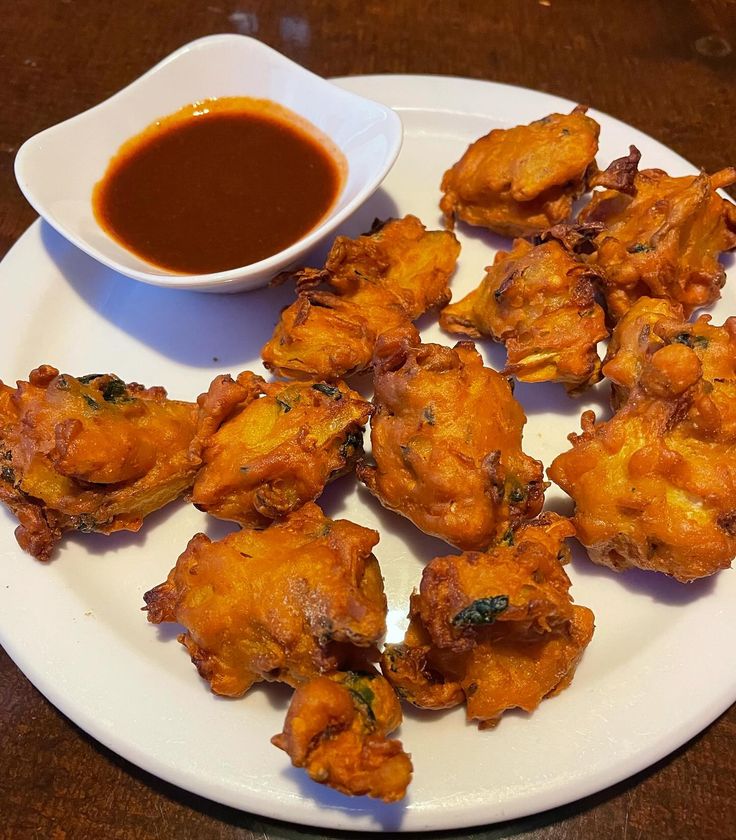 some fried food on a white plate with dipping sauce