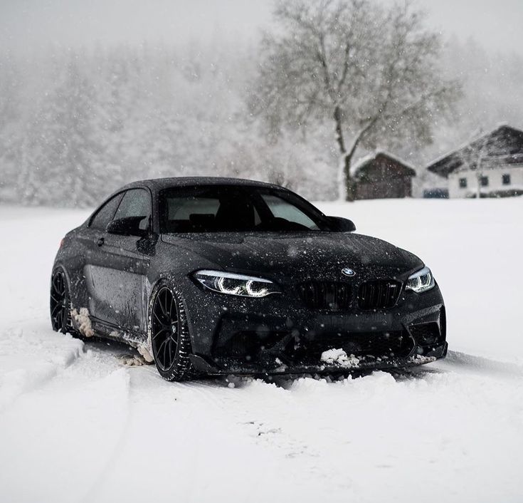 a black car is driving through the snow