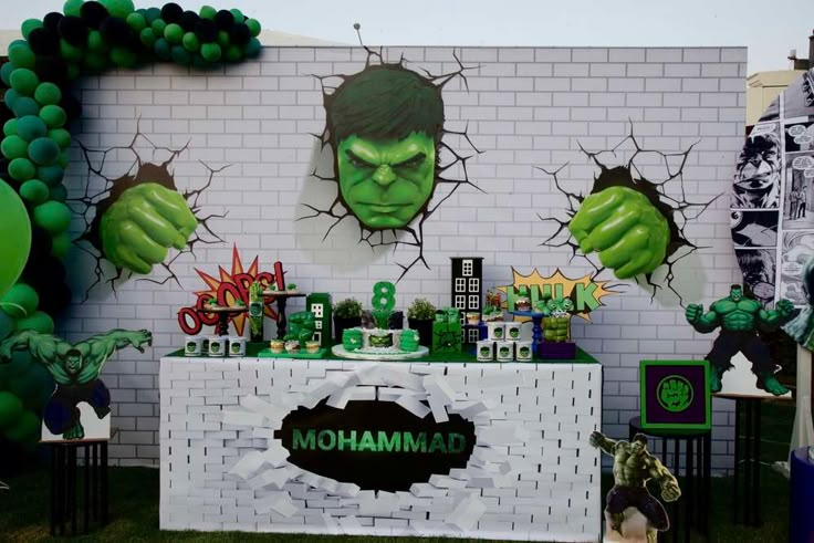 an incredible hulk birthday party with green balloons and decorations on the wall, including balloon archs