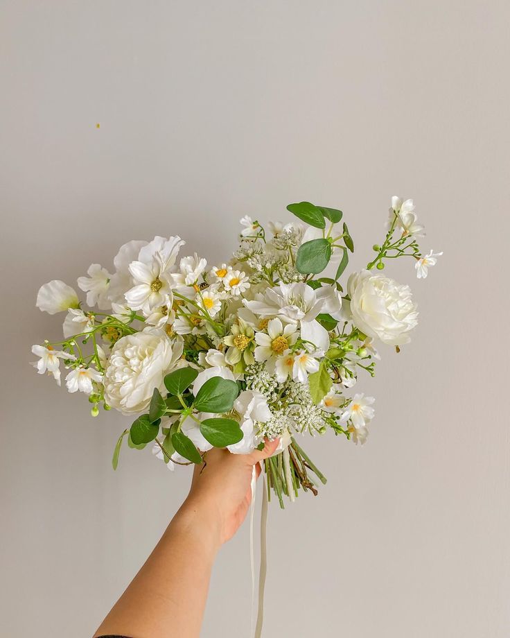 a hand holding a bouquet of white flowers