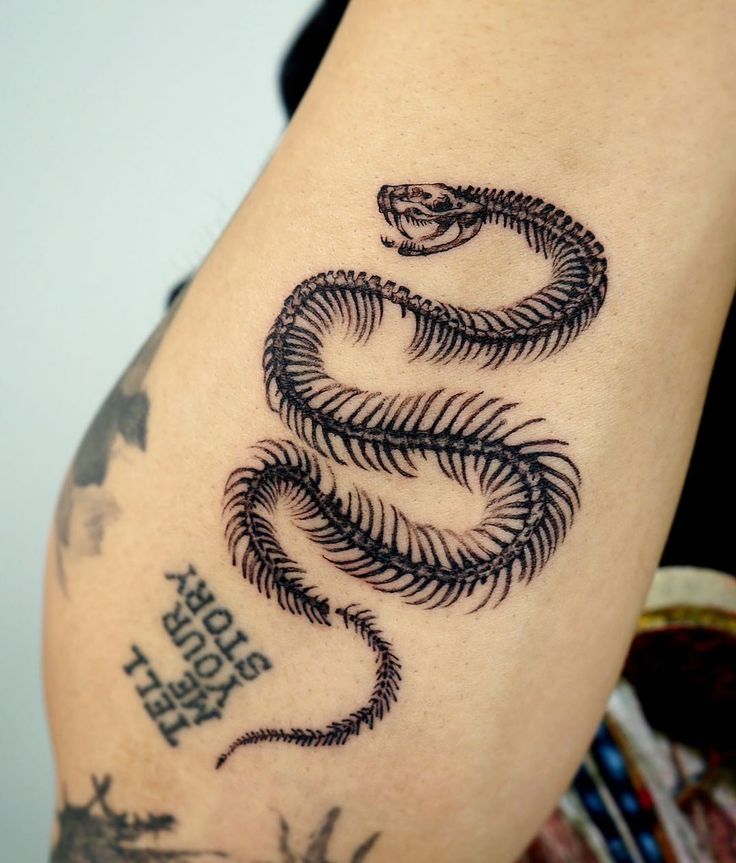 a black and white photo of a snake tattoo on the arm