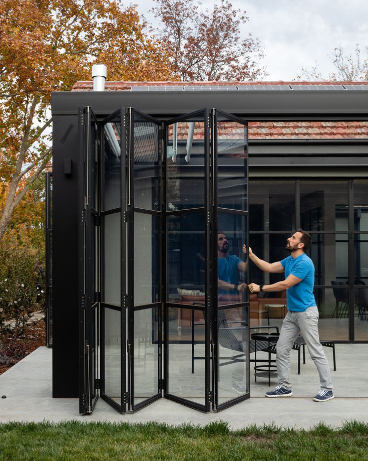 a man standing in front of a black glass room divider on the side of a building