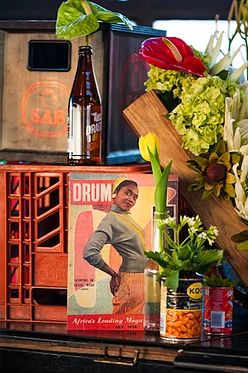 flowers and beer are sitting on top of an old piano with music memorabilia in the background