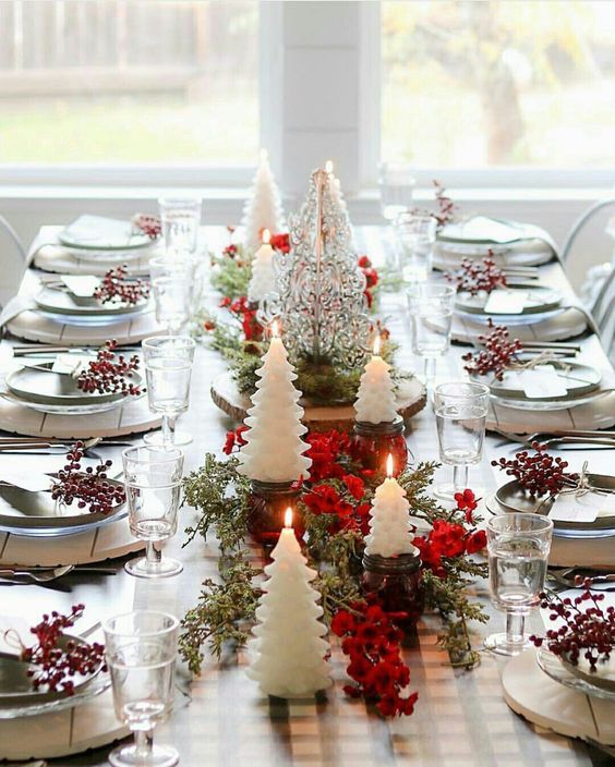 a dining room table decorated for christmas with candles and greenery on the centerpiece