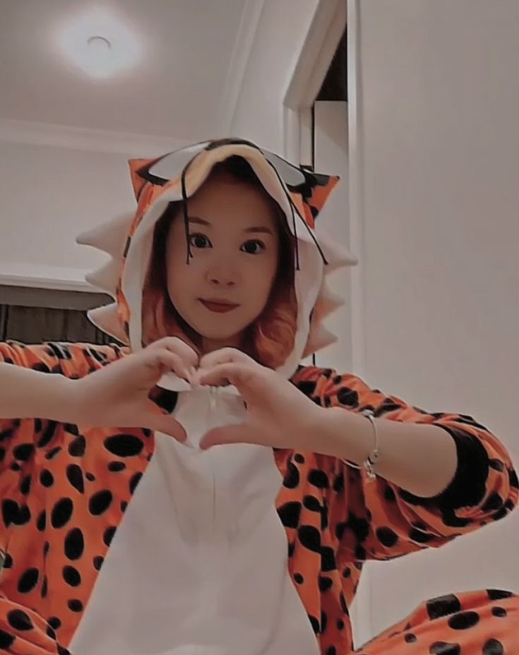 a woman in a cat costume making a heart with her hands while sitting on the floor