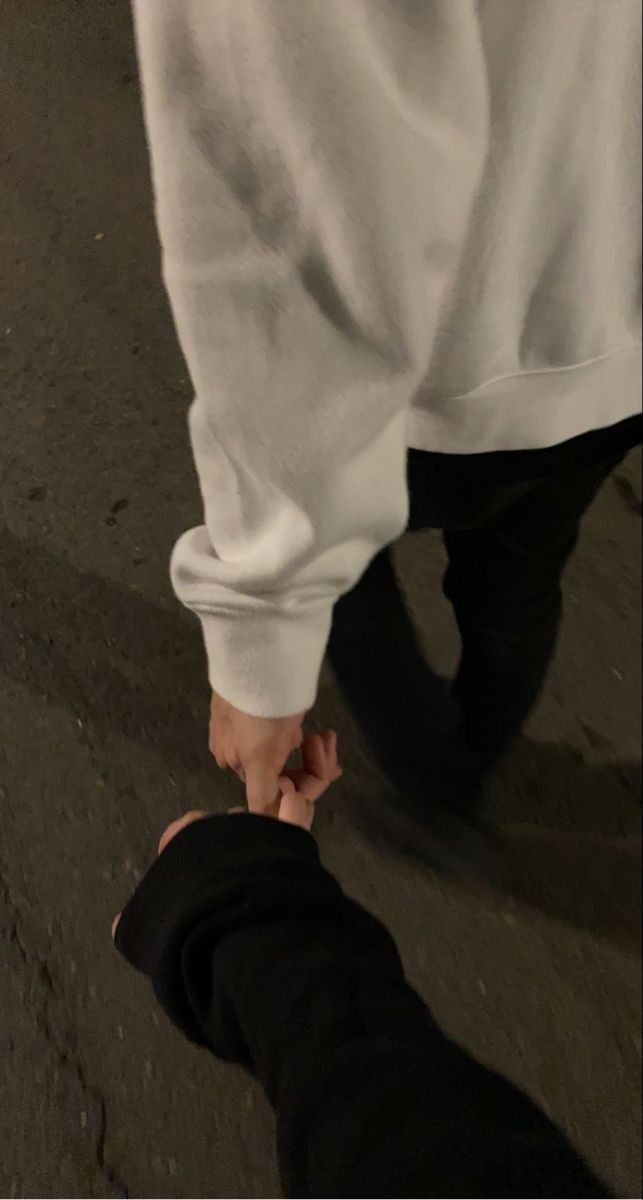 two people holding hands while walking down the street