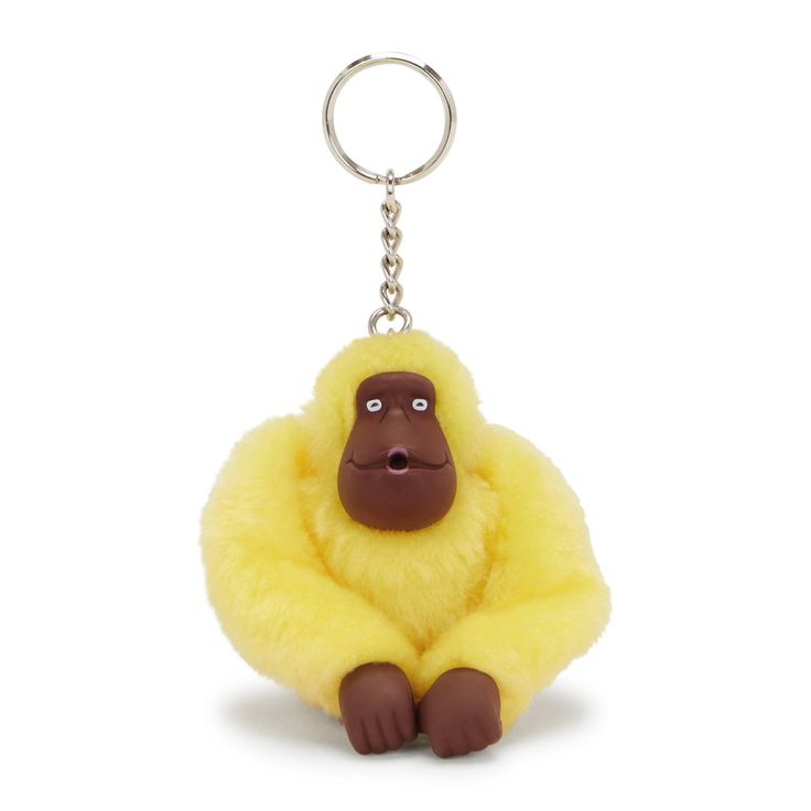 a yellow stuffed animal keychain with a brown gorilla on it's back