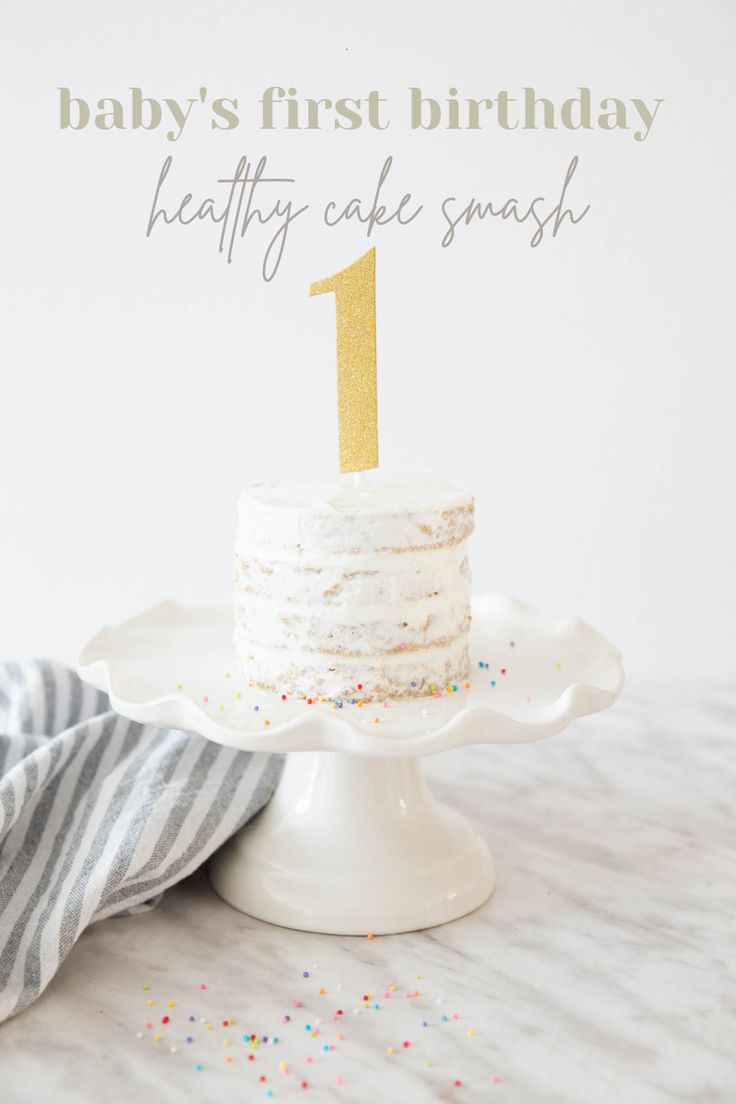 a white cake sitting on top of a table next to a striped napkin and cup