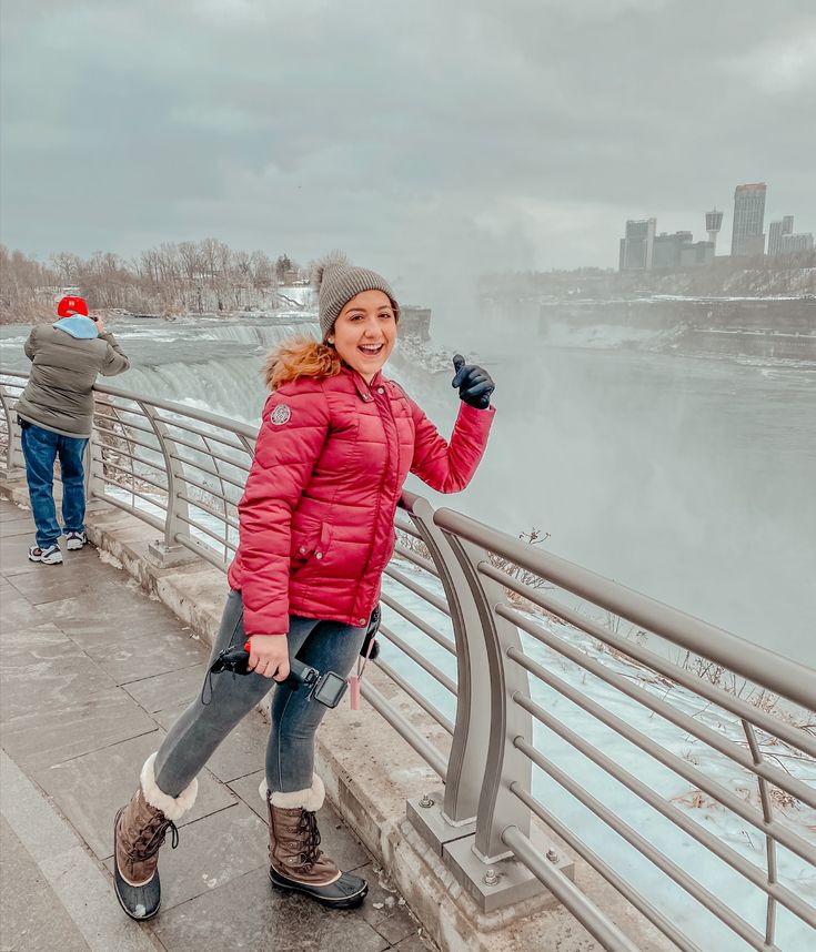 a woman standing next to a railing near the water