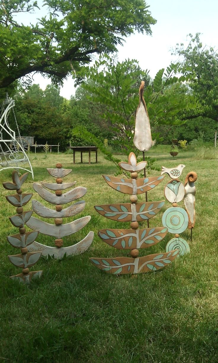 three wooden sculptures sitting on top of a lush green field