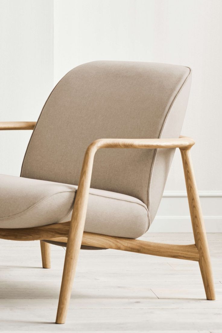 a beige chair sitting on top of a hard wood floor next to a white wall