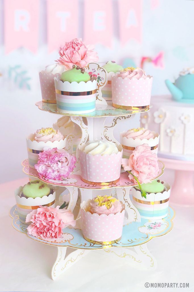 there are many cupcakes on the tiered cake stand that is decorated in pastel colors