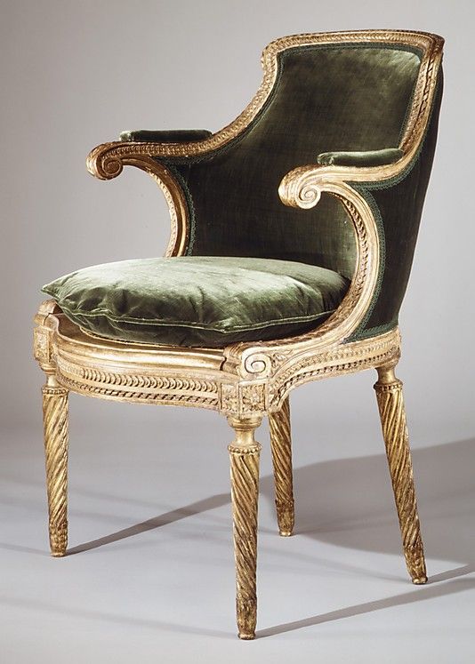 an antique chair with green velvet upholstered on the seat and back, in front of a white background