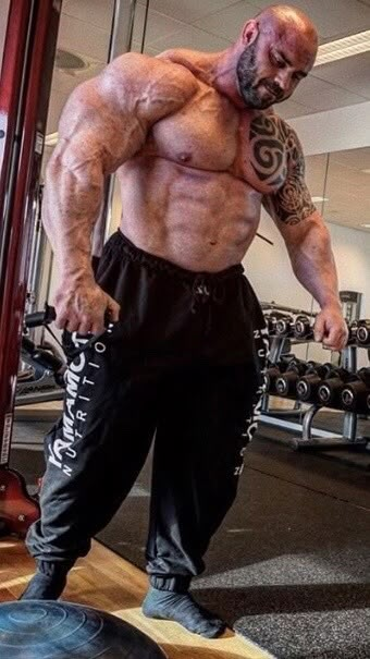 a man standing on top of a gym floor in front of a barbell machine