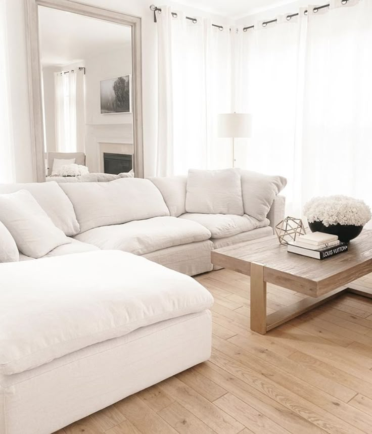 a large white couch sitting in a living room next to a coffee table and mirror