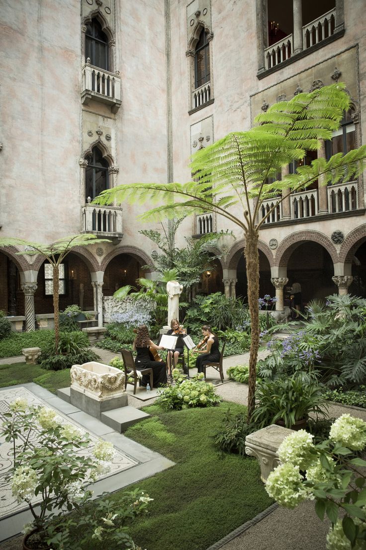 two people sitting on chairs in the middle of a courtyard with plants and flowers around them