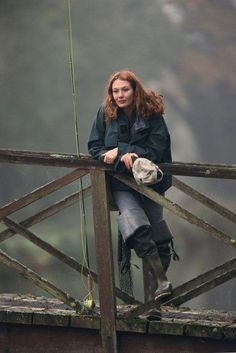 a woman sitting on top of a wooden bridge