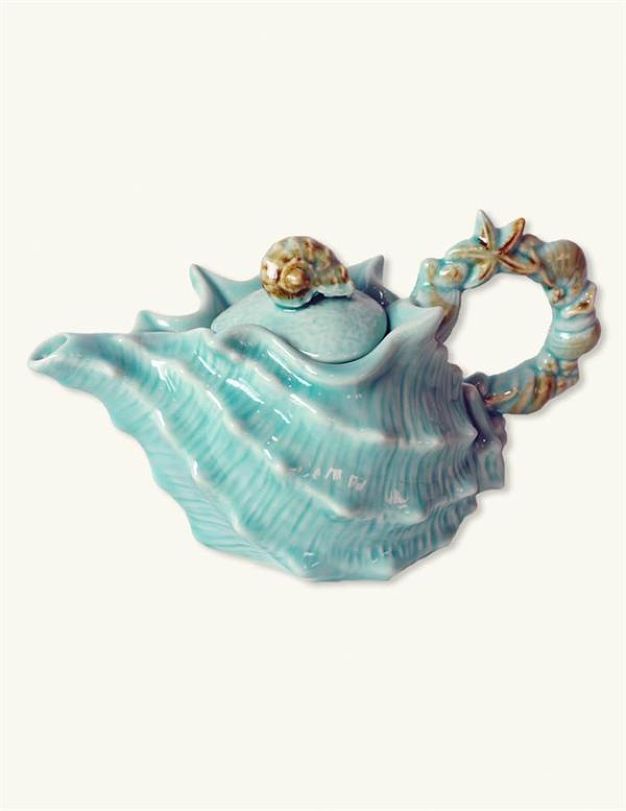 a ceramic teapot shaped like a seashell with two gold fish on it's sides