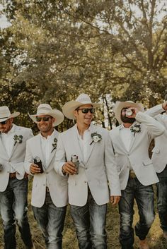 a group of men standing next to each other wearing white suits and hats with beer in their hands