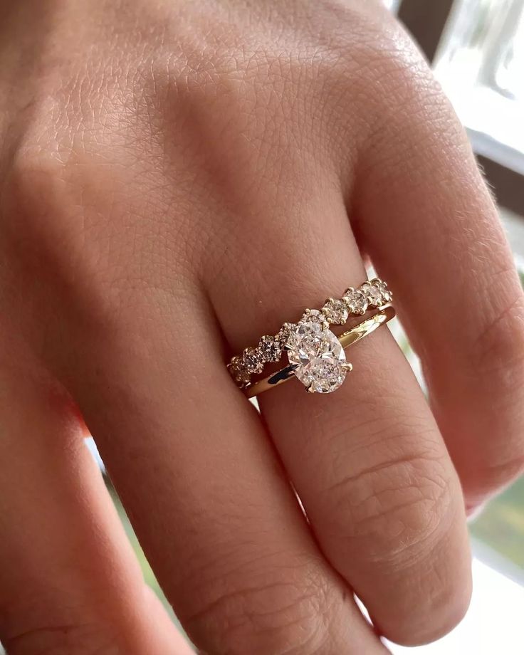 a woman's hand with a gold ring and three stones on the middle finger