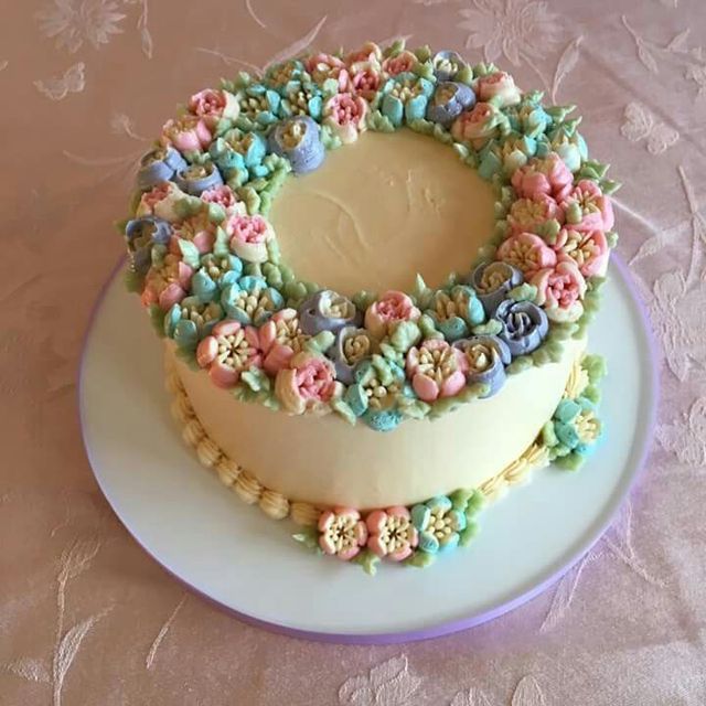 there is a cake decorated with flowers on the plate and frosting in the shape of a wreath