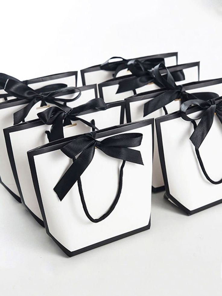 six black and white gift bags with bows on the handles, tied in satin ribbon