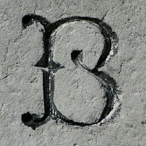 the letter s is written in sand with black ink