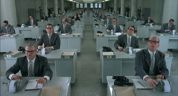 several men in suits and ties sitting at desks