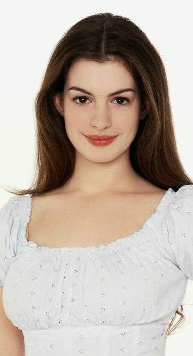 a woman with long brown hair wearing a white dress and smiling at the camera while standing in front of a white background