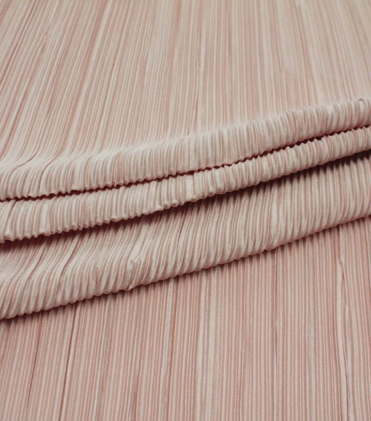 a close up view of a pink bed sheet with pleated edges and two pillows