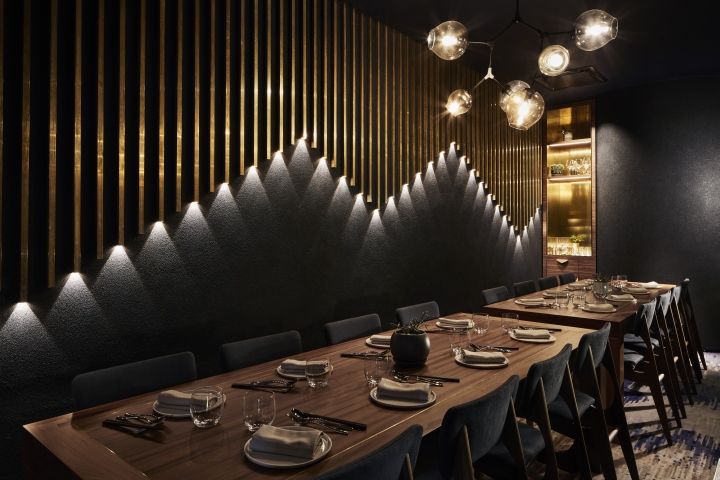 a long table with plates and silverware on it in front of a black wall