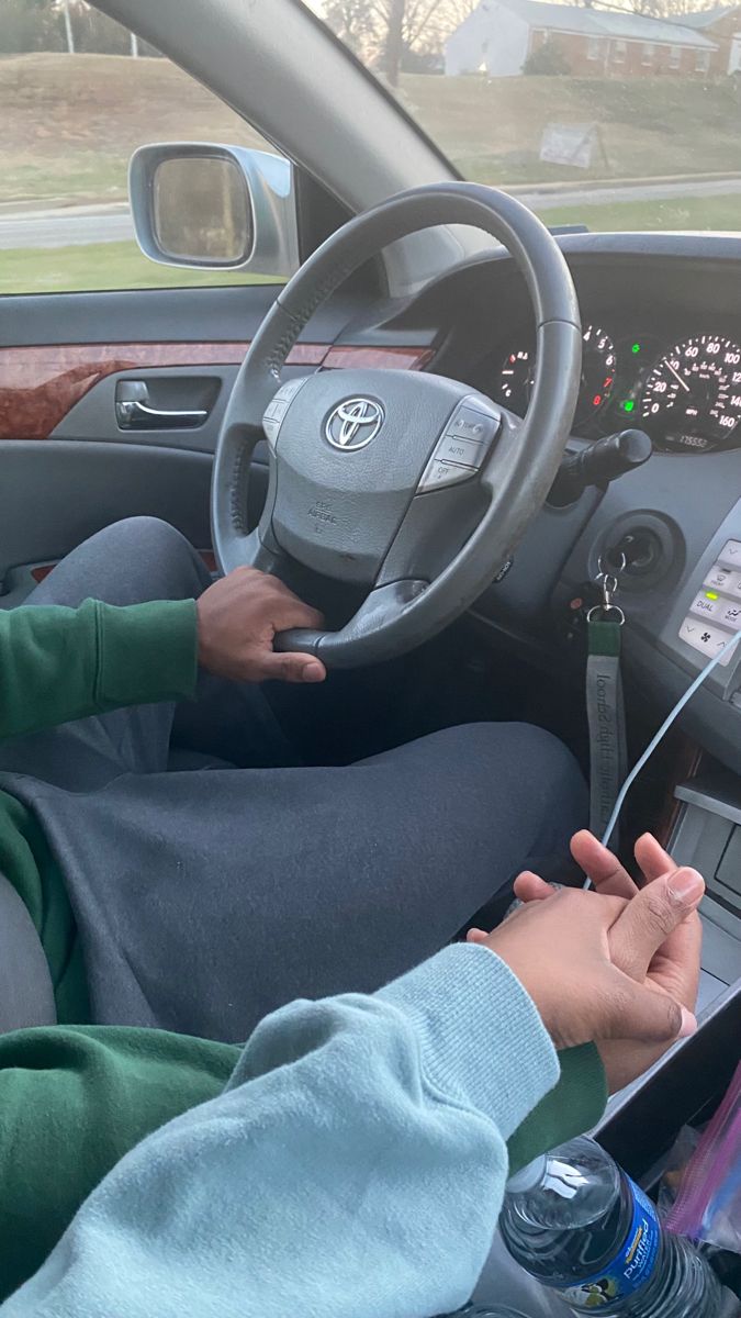 a person sitting in the driver's seat of a car using their cell phone