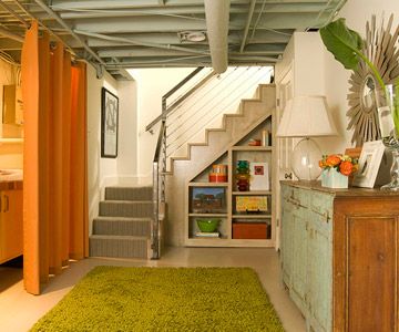 a living room filled with furniture next to a stair case and green rug on the floor