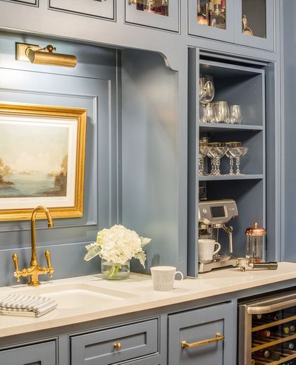 a kitchen with blue cabinets and white counter tops, gold trim around the sink area