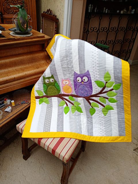 two owls sitting on a tree branch quilted onto a chair in front of a piano