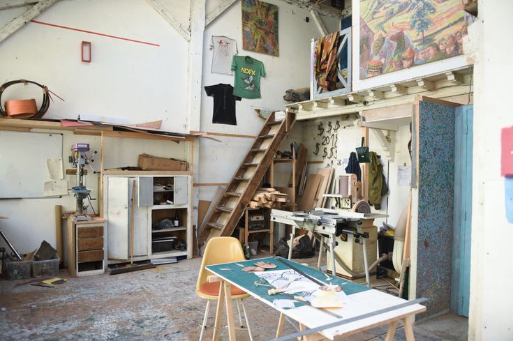 a room filled with lots of clutter next to a wooden table and ladders