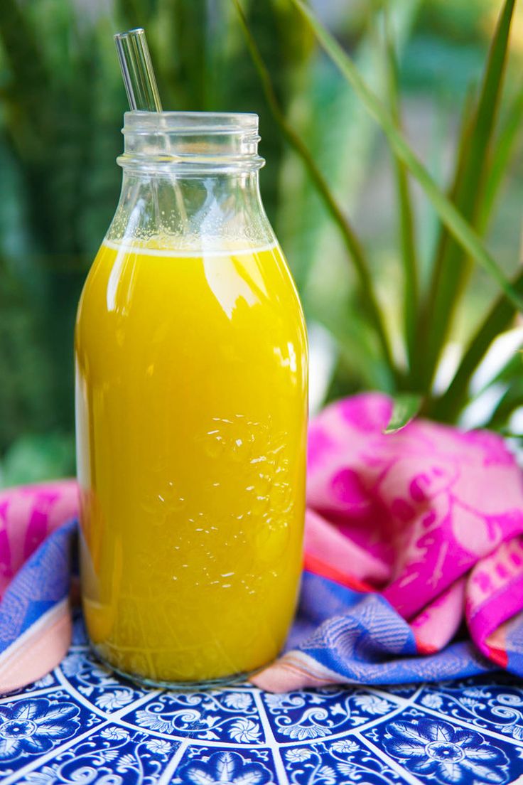 a glass jar filled with yellow liquid sitting on top of a blue and white cloth