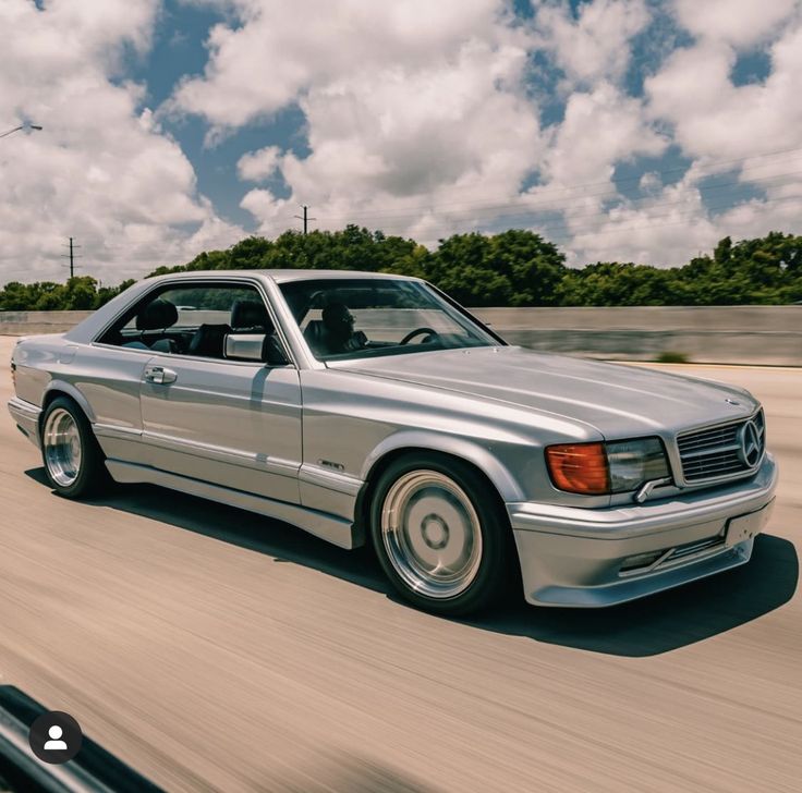 a silver mercedes benz coupe driving down the road