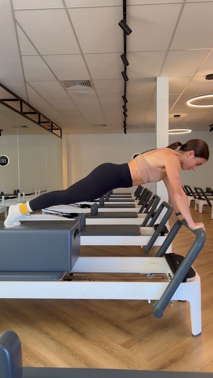 a man does push ups on a treadmill in a gym with rows of machines