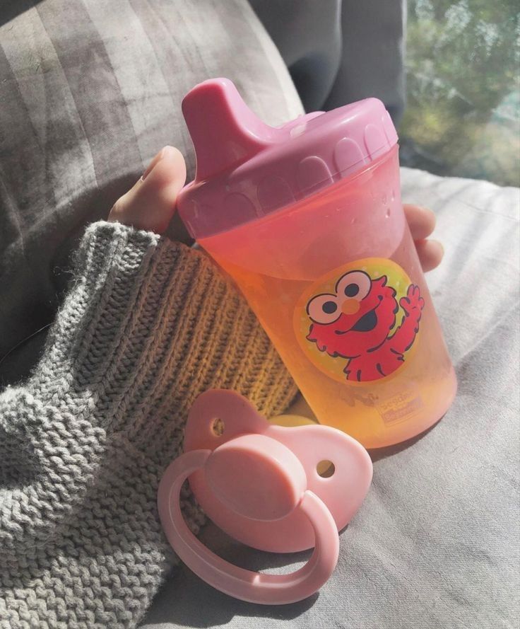 a baby bottle sitting on top of a couch next to a pacifier