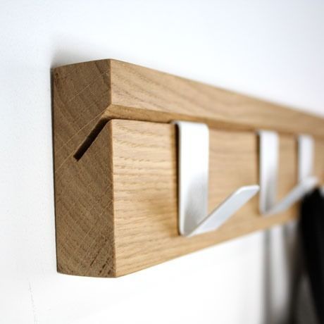 a coat rack made out of wood and metal hooks on the side of a wall