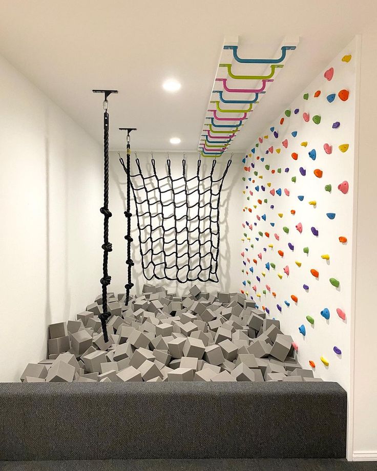 an art installation in the corner of a room with climbing ropes and balls on the wall