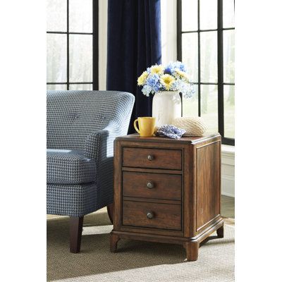 a chair and table with flowers on it in front of a window, next to a couch