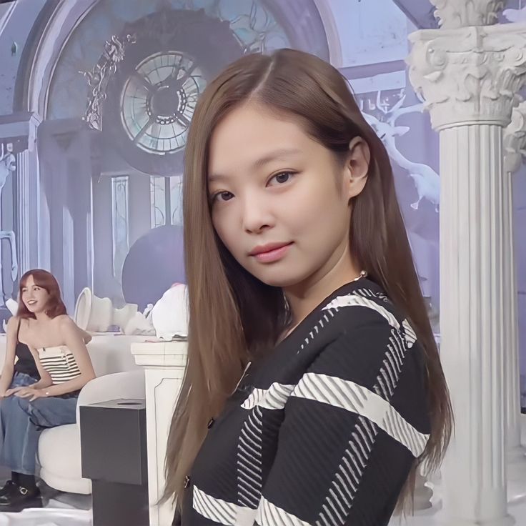 two women sitting on couches in front of a wall with clocks and columns behind them