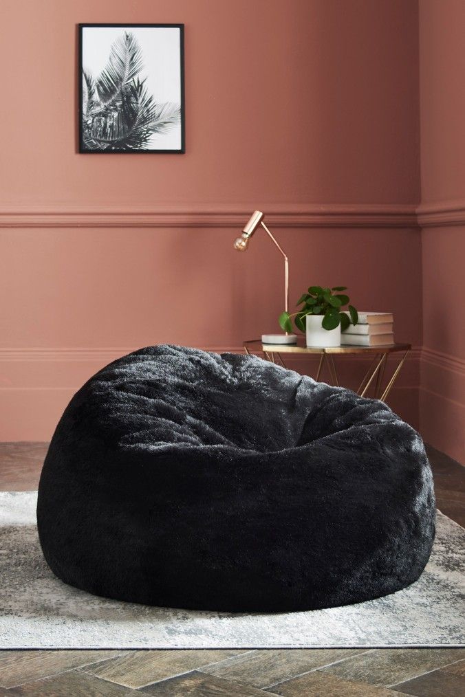 a bean bag chair sitting on top of a rug in front of a pink wall