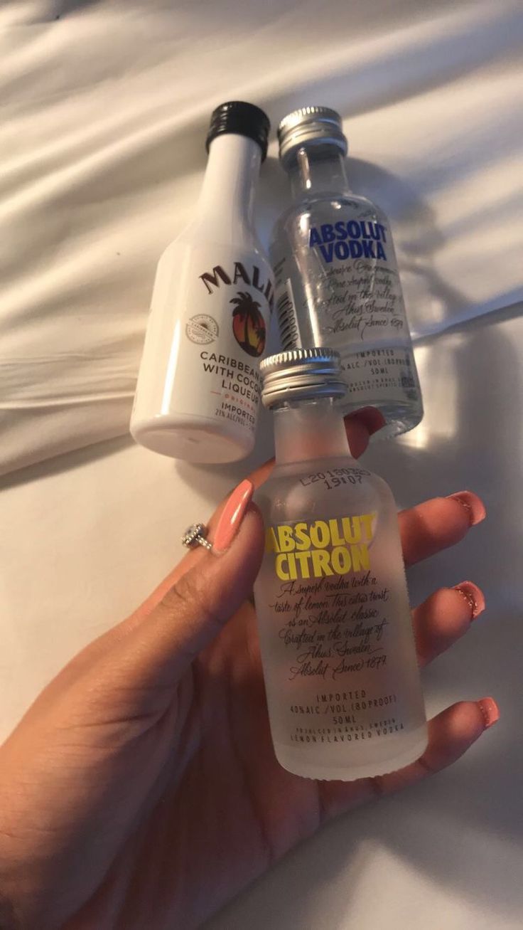 two bottles of liquid sitting on top of a bed next to someone's hand