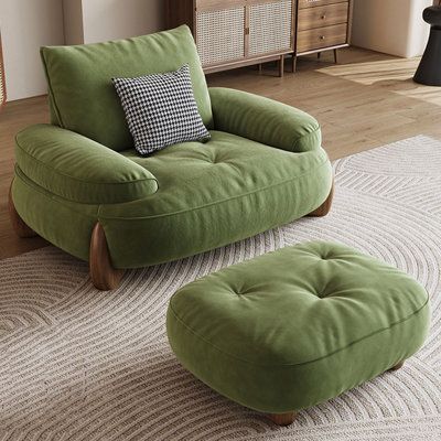 a green chair and ottoman sitting on top of a rug in front of a dresser