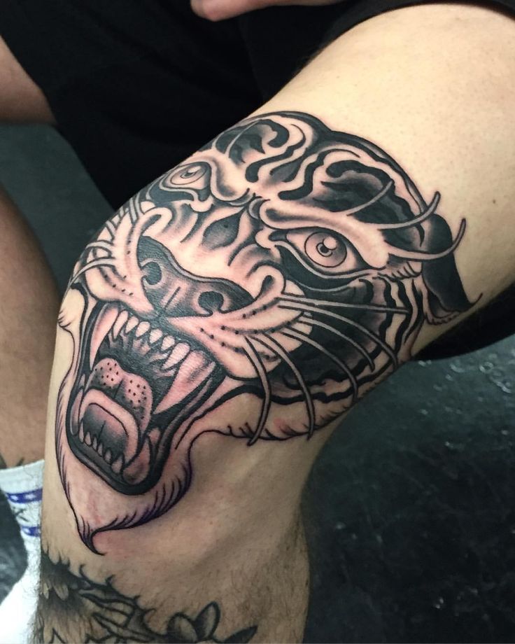 a man with a tattoo on his leg showing the tiger's teeth and claws